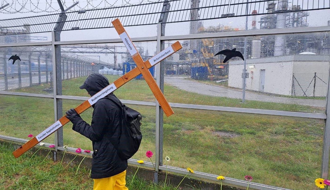 Demonstrant mit Kreuz vor der Erdölraffinerie in Schwechat