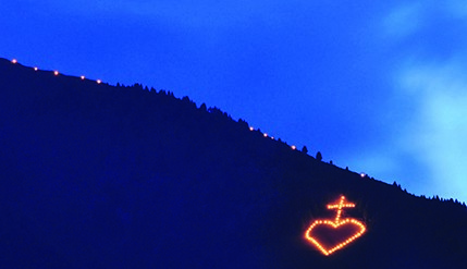 Leuchtendes Herz mit Kreuz auf einem Berg