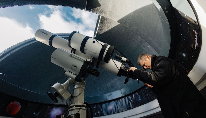 Pater Christoph Gerhard schaut durch ein Teleskop in den Himmel