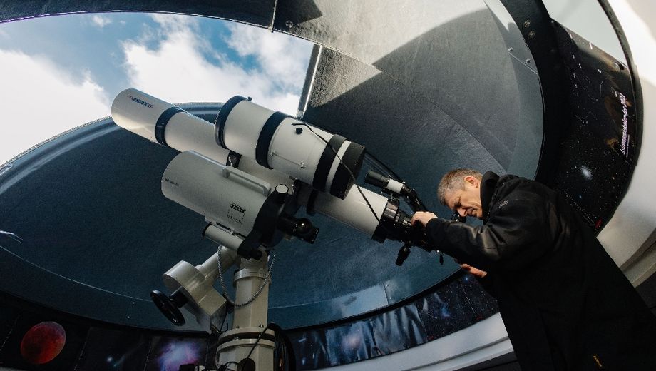 Pater Christoph Gerhard schaut durch ein Teleskop in den Himmel