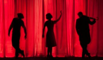 Drei gestalten vor einem rioten Bühnenvorhang