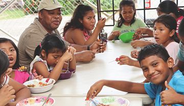 Mann und Kinder sitzen am Tisch und essen