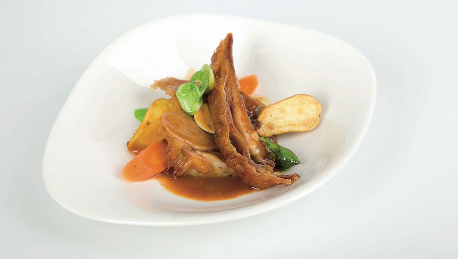 Lammbraten mit brauner Sauce auf einem Teller angerichtet mit gebratenen Kartoffeln, Karotten und Lauch