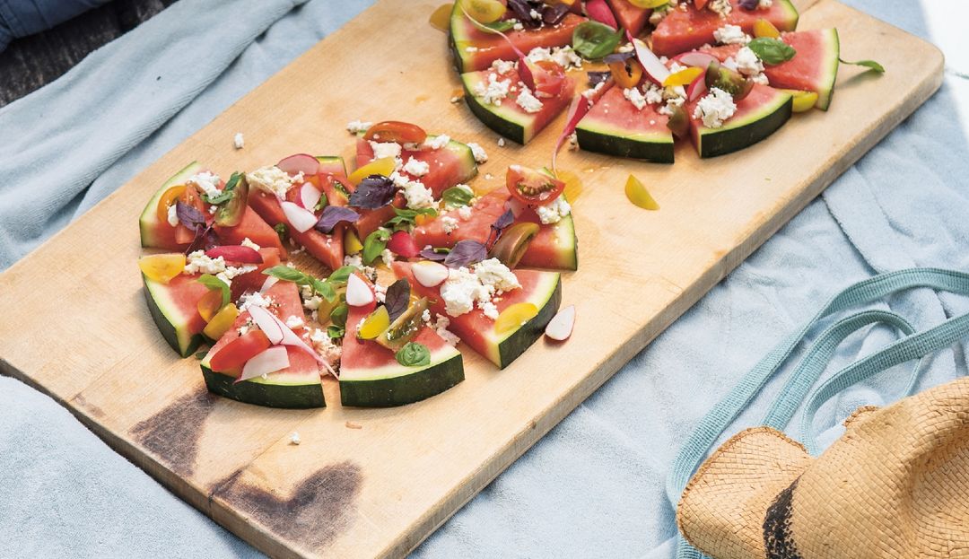 Melonenspalten belegt mit Radieschen, Tomaten, Pfirsich und Feta