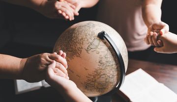 Foto eines Globus' und Menschen, die einander an den Händen halten