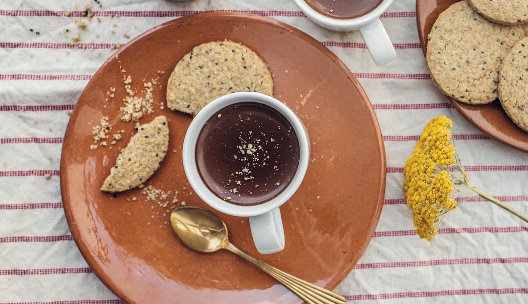 Köstliches Dessert für alle, die bewusst genießen möchten: Polentakekse mit Schokomousse Teller mit angebissenem Keks, Kaffeetasse, Löffel auf Dessertteller
