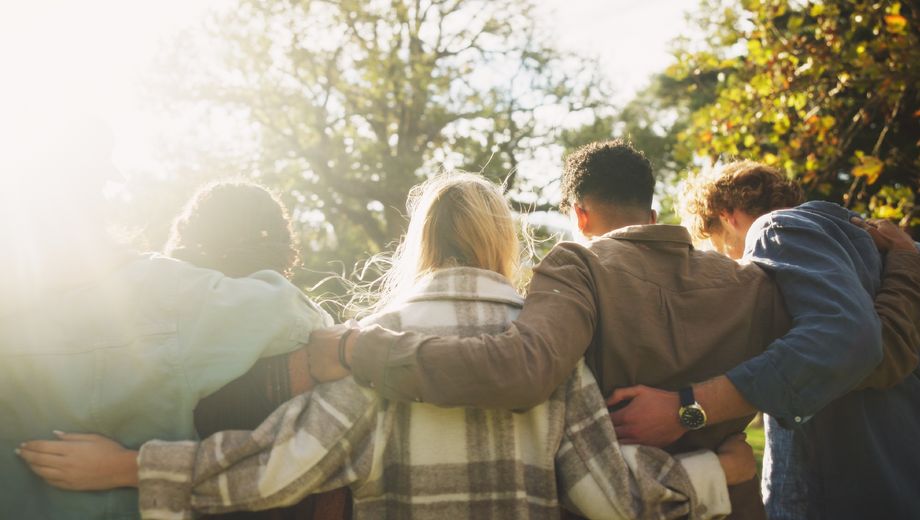 Foto mehrerer Menschen, die einander freundschaftlich in den Arm nehmen