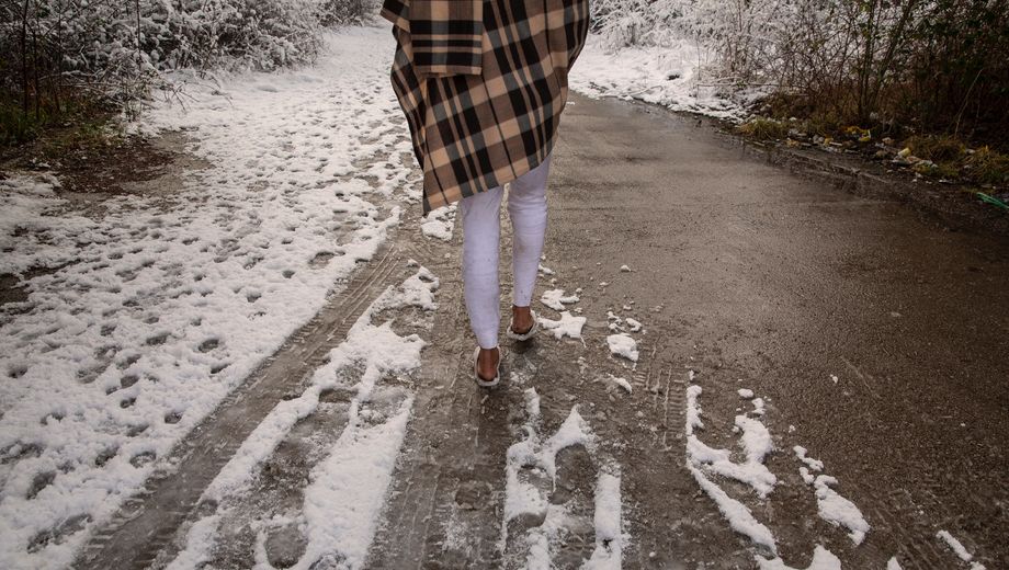 Foto einer jungen Frau, die einen verschneiten Pfad entlanggeht