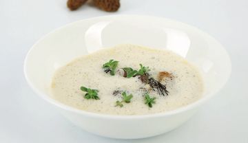 Ein Teller mit heller Suppe mit Kräutern bestreut