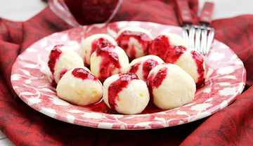 Teller voller Topfenknödel mit roter Sauce