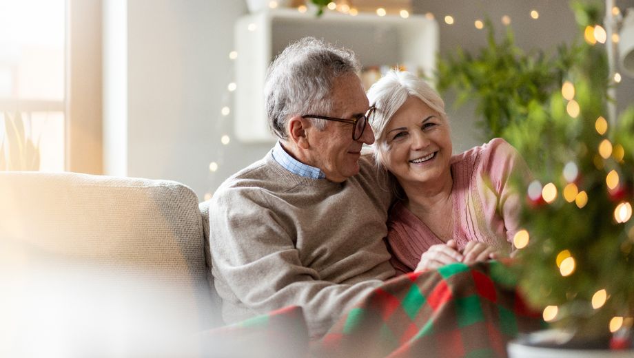 Ein älteres Paar sitzt in einem weihnachtlich geschmückten Wohnzimmer