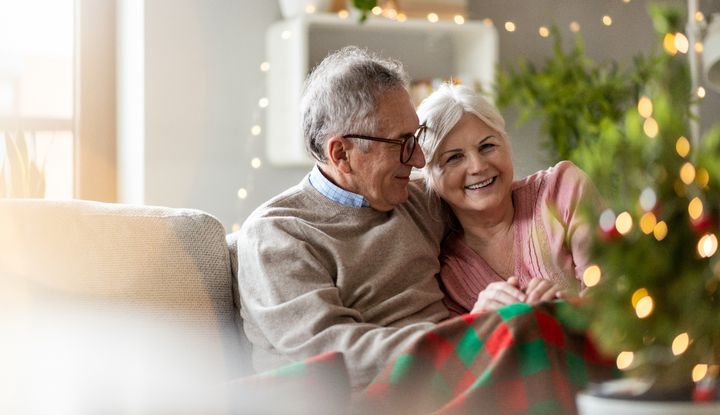 Ein &auml;lteres Paar sitzt in einem weihnachtlich geschm&uuml;ckten Wohnzimmer