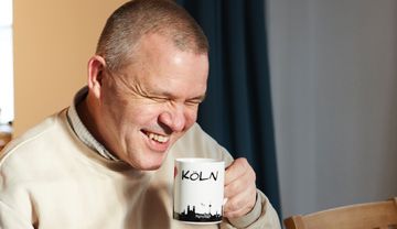 Foto eines lachenden Pater Norbert Cuypers beim Kaffeetrinken