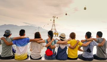 Junge Menschen sitzen im Sonnenuntergang an einem Ufer