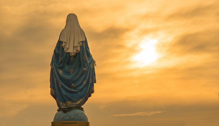 Die R&uuml;ckseite einer Marienstatur, die in den gelb leutenden Himmel blickt