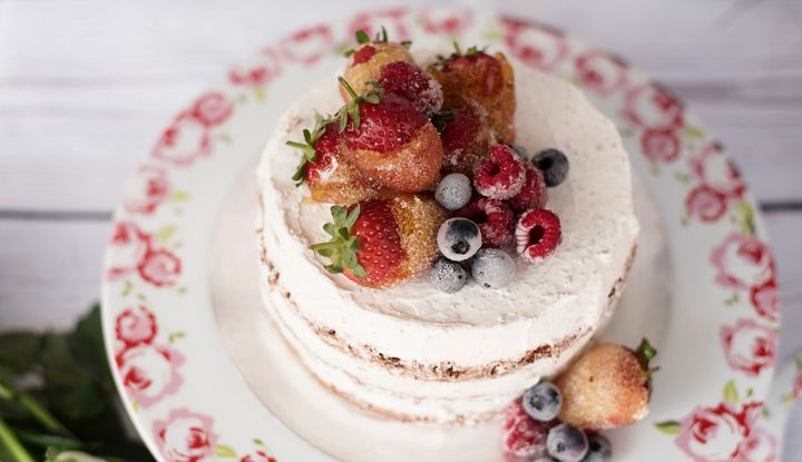 Mit Beeren dekorierte Sahnetorte auf einem gebl&uuml;mten Servierteller
