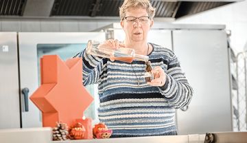 Frau schüttet Getränk in eine Flasche, weihnachtlich dekoriertes Ambiente