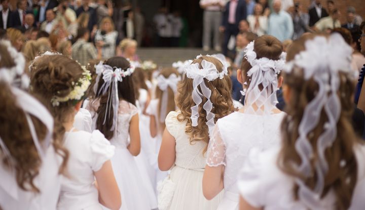 Kommunionskinder stehen im wei&szlig;en Kleid vor dem Kircheneingang
