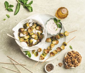 Ein Teller mit Rosenkohlspießen, eine Schale mit Dip