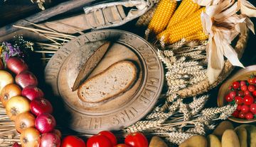 Ein gedeckter Tisch mit Brot, Äpfeln und Ähren