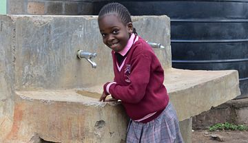 Ein Mädchen steht an einem Steinwaschbecken
