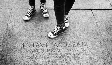 Zwei Personen mit Turnschuhen stehen auf einer Steinplatte, in die das Zitat „I have a dream“ von Martin Luther King Jr. eingraviert ist