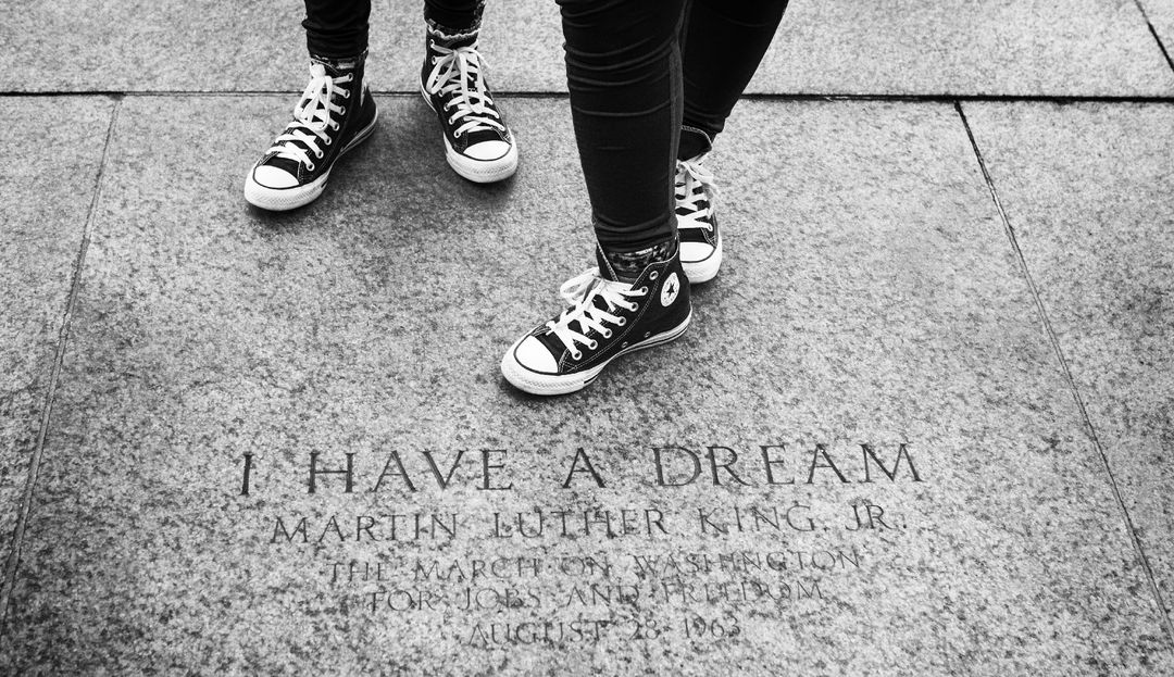 Zwei Personen mit Turnschuhen stehen auf einer Steinplatte, in die das Zitat „I have a dream“ von Martin Luther King Jr. eingraviert ist