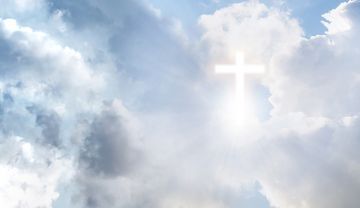 hell aufleuchtendes Kreuz zwischen Wolken am Himmel