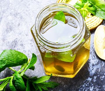 Ein Glas voller Zitronenmelissen-Gelee, dekoriert mit Zitronenmelissen-Blättern