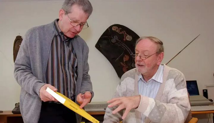 Zwei M&auml;nner schauen sich die Zeitschrift an