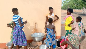 Frauen in Togo mit Schöpfgefäßen fürs Wasserholen