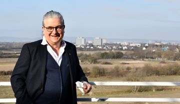 Jesuitenpater Tobias Zimmermann SJ steht im Freien vor einer Landschaft mit Feldern und Stadt im Hintergrund