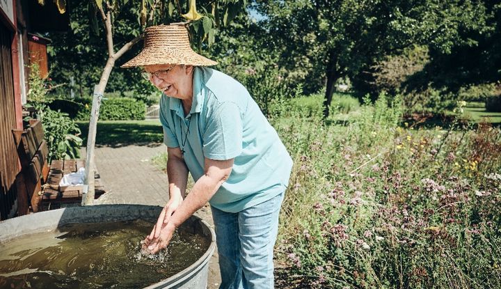 Frau mit Sonnenhut an einem Brunnen